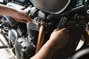 Mechanic using a wrench and socket on exhaust pipe of a motorcycle .maintenance,repair motorcycle concept in garage .selective focus photo