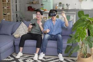 Young smiling gay couple playing video games in the living room at home, LGBTQ and diversity photo