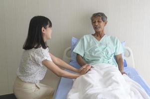 Young daughter visiting sick old father in hospital, healthcare and medical concept photo