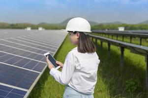 ingeniera con casco en granja de células fotovoltaicas o campo de paneles solares, energía ecológica y limpia. foto