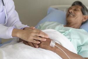 Doctor holding senior patient's hand in hospital, health care and medical concept photo