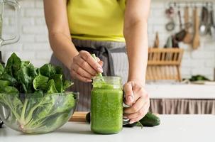 primer plano de una mujer joven sosteniendo un frasco de batido verde foto