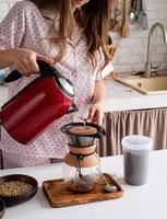 mujer joven en pijama encantador haciendo café en la cocina de casa foto