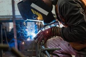 los trabajadores de la máscara están soldando acero en el taller foto