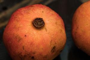 Fresh colorful pomegranates fruits close up on black table photo