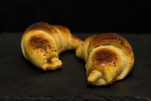 croissant with poppy and jam on black table, fresh hommade bakery close up photo