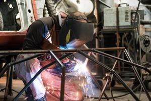 Workers in the mask are welding steel in workshop photo