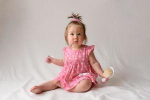 Little girl 6 months old with a comb in hand on a white background. photo