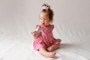 Little girl 6 months old with a comb in hand on a white background. photo