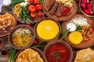 comida rumana casera con pasteles, polenta, borscht, verduras, pescado, carne, estofado, queso y vino. platos tradicionales de rumania y la república de moldavia. foto