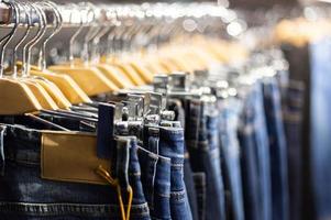 fila de jeans azules y negros colgados en perchas en una tienda. foto