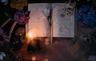 libro viejo abierto con hechizos mágicos, runas, vela negra foto