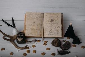 Open old book with magic spells, runes, black candle photo