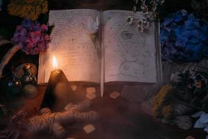 libro viejo abierto con hechizos mágicos, runas, vela negra foto