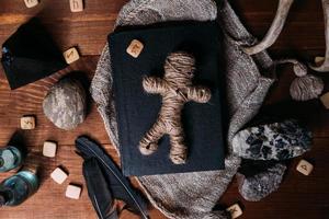 A voodoo doll made of rope lies on a black book photo