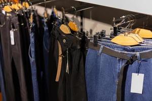 Row of hanged blue and black jeans on hangers in a shop. photo