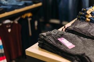 Stack of blue and black jeans in a shop. Concept of shopping and jeans fashion. photo