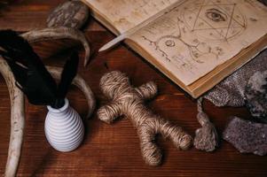 un muñeco vudú hecho de cuerda yace con un viejo libro grimorio foto