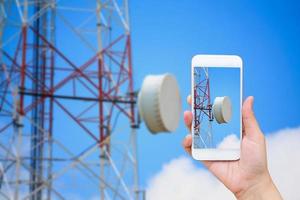 teléfono inteligente móvil de mano con torre de telecomunicaciones foto