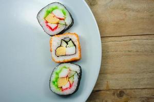 Sushi maki on a plate over wooden table photo