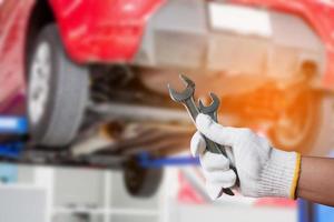 Car mechanic holding wrench at the car repair garage photo