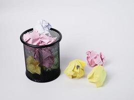 A small black basket made of round steel. Used to put garbage, documents that are not work and have been crushed so much that it overflows outside. In the white background there is copy space. photo