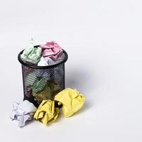 A small black basket made of round steel. Used to put garbage, documents that are not work and have been crushed so much that it overflows outside. In the white background there is copy space. photo
