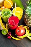 Batido saludable de frutas y verduras frescas con ingredientes variados servidos en botellas de vidrio con pajitas aisladas en fondo blanco en una pancarta panorámica foto