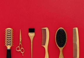 Background with hairdressing tools on red. Hair salon accessories gold, hair combs, scissors. Banner and template for design with space for text.