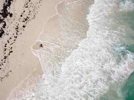 Aerial view of the beach, waves making a heart shape around a woman in the hat photo