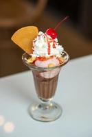 helado de fresa y chocolate con crema batida de cereza roja foto