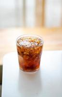 refresco con hielo en un vaso sobre una mesa blanca foto