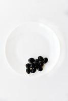 Pickled black olives on a white plate with a fork photo