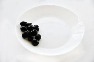 Pickled black olives on a white plate with a fork photo