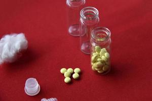 Glass vials with pills on a red background photo