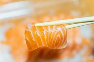 Salmon that has been pinched with chopsticks on a blurred background photo