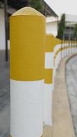 Yellow and white concrete columns on a concrete pavement near the car park. photo