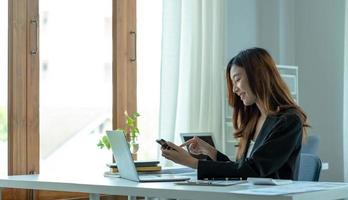 Asian businesswoman relax and enjoy playing mobile phone at office. photo