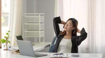 Young Asian businesswoman stretching arms raised relaxing at the office. photo