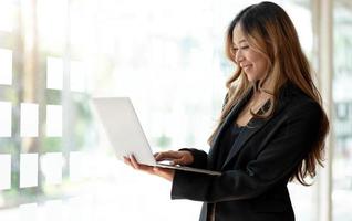 Young Asian business woman working online on a laptop in office. photo