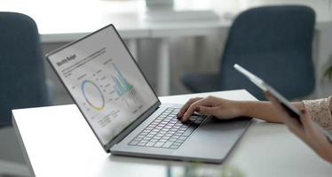 imagen de primer plano de una mujer de negocios asiática trabajando y escribiendo en el teclado de un portátil en la oficina foto