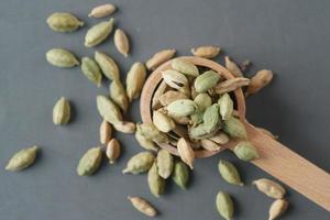 Cerca de cardamomo en una cuchara en la mesa foto