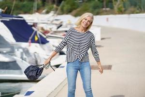 Happy woman in her 60s strolling along a seaside spot near the beach. photo