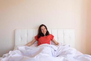 la niña se sienta en la cama y se estira, la mujer se despertó foto