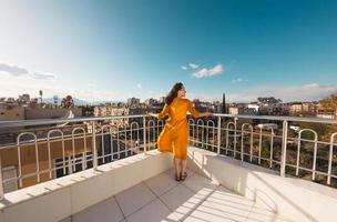 an attractive girl looks at the city and the wind inflates her dress photo