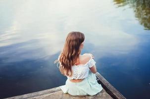 niña sentada junto al río foto