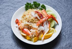 Fried Rice crab seafood - Healthy food fried rice with Crab legs with egg lemon and cucumber on white plate photo