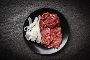 conjunto de rebanadas de carne de res e hígado en un plato negro de fondo oscuro para cocidos o sukiyaki shabu shabu comidas japonesas cocina asiática - carne de res fresca cruda foto