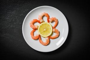 Shrimps prawns served decorate seafood plate and lemon on dark background photo