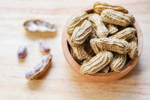 Peanut in wooden cup bowl and wood background top view - Boiled peanuts photo